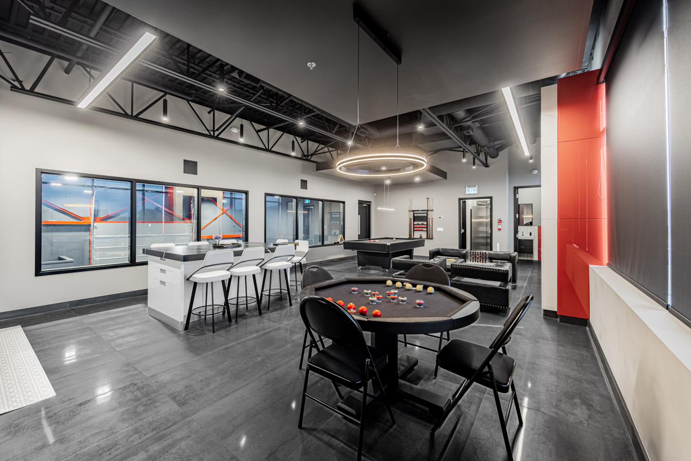 Second-floor lounge with pool table and kitchen, evening.